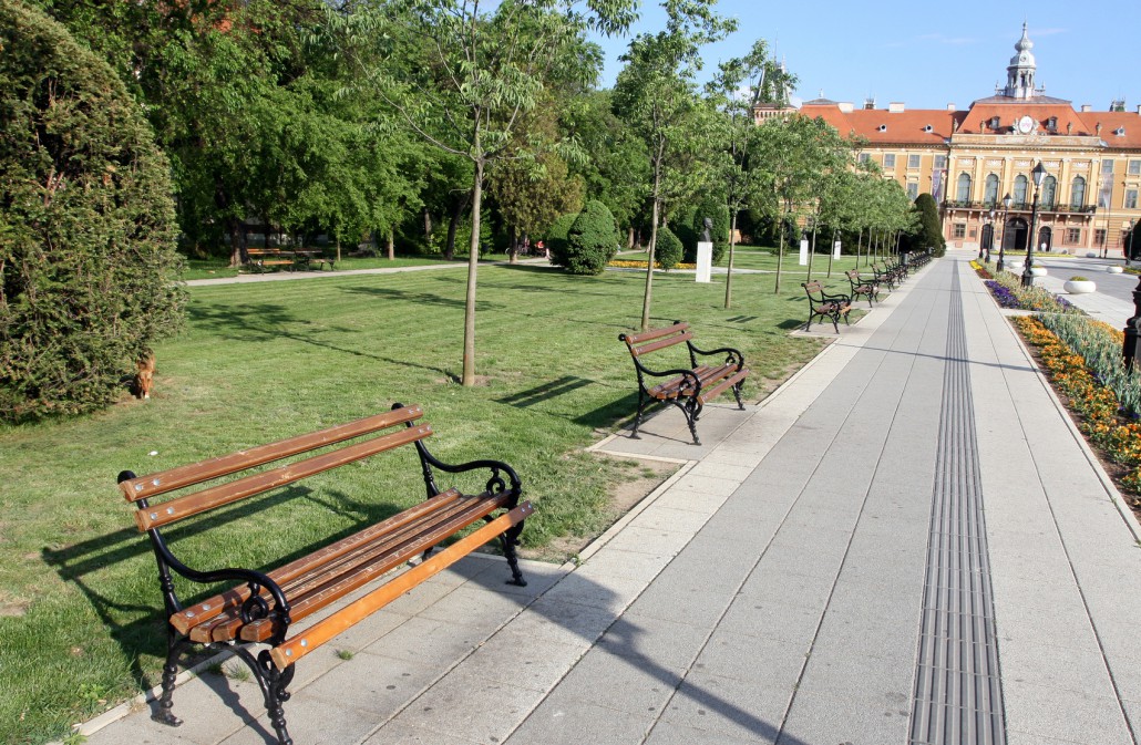 Bänke in einem Park und ein Gehweg mit Blindenleitsystem. Barrierefreiheit